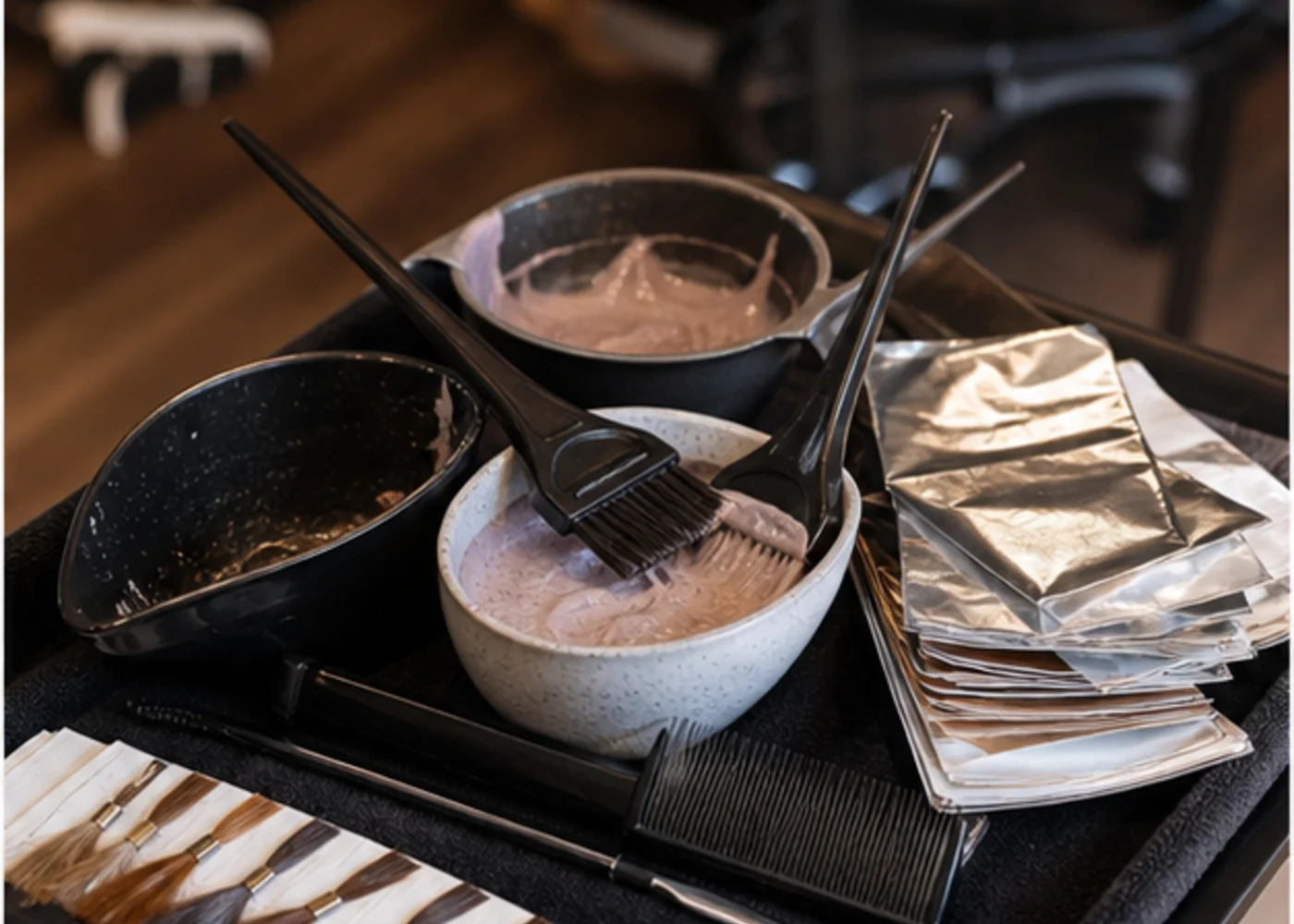 Salon colour bowls, tint brushes, foils, and service tools on a trolley.